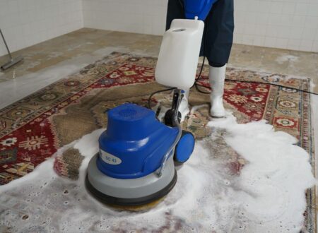 Deep cleaning of an Oriental rug using a rotary machine and foam shampoo, performed by a professional rug cleaner in a tiled cleaning facility