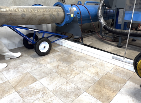 Commercial rug water extraction machine used for deep cleaning and drying area rugs in a professional cleaning facility with tiled flooring.
