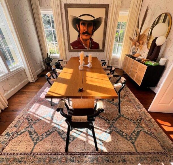 A stylish dining room with a large, vintage Oriental rug featuring intricate beige and blue patterns. Sunlight highlights the rug's texture, emphasizing the need for expert cleaning to maintain its beauty and longevity.