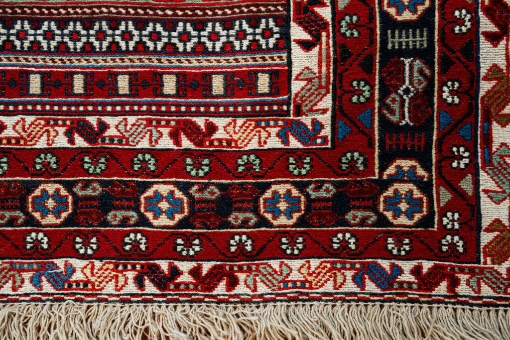 Close-up of a traditional handmade Moroccan rug with red, blue, green, and cream geometric patterns and natural fringe – RugGuys professional rug cleaning DFW