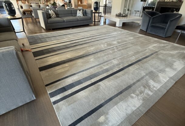 Modern living room with a freshly cleaned striped area rug, surrounded by elegant furniture and a clean, polished floor.